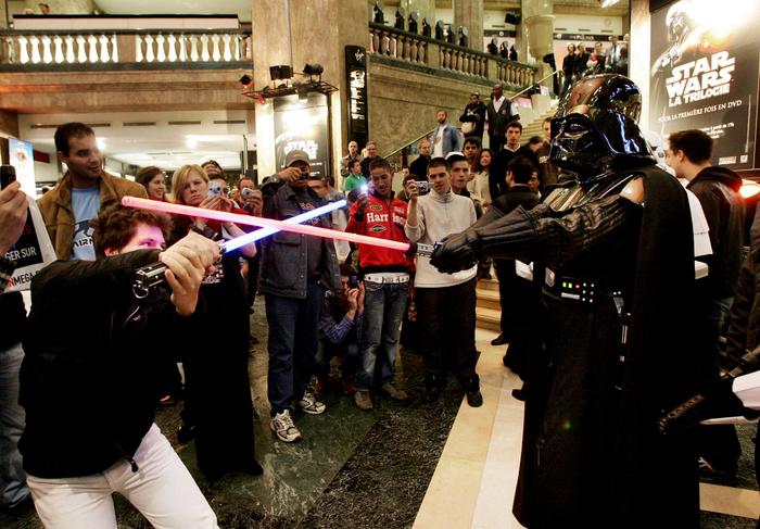 Un fan de Star Wars se bat avec un sabre laser contre « Dark Vador » dans un célèbre magasin des Champs-Élysées à Paris, le 21 septembre 2004.