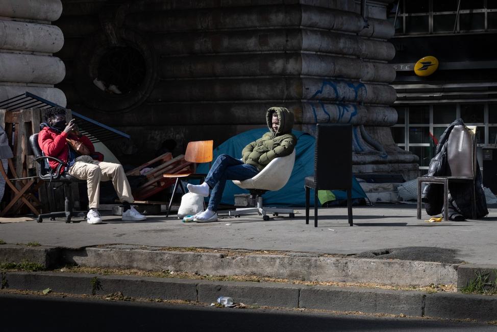 Des hommes sont assis à côté des tentes provisoires de migrants à Paris, le 22 avril 2026.