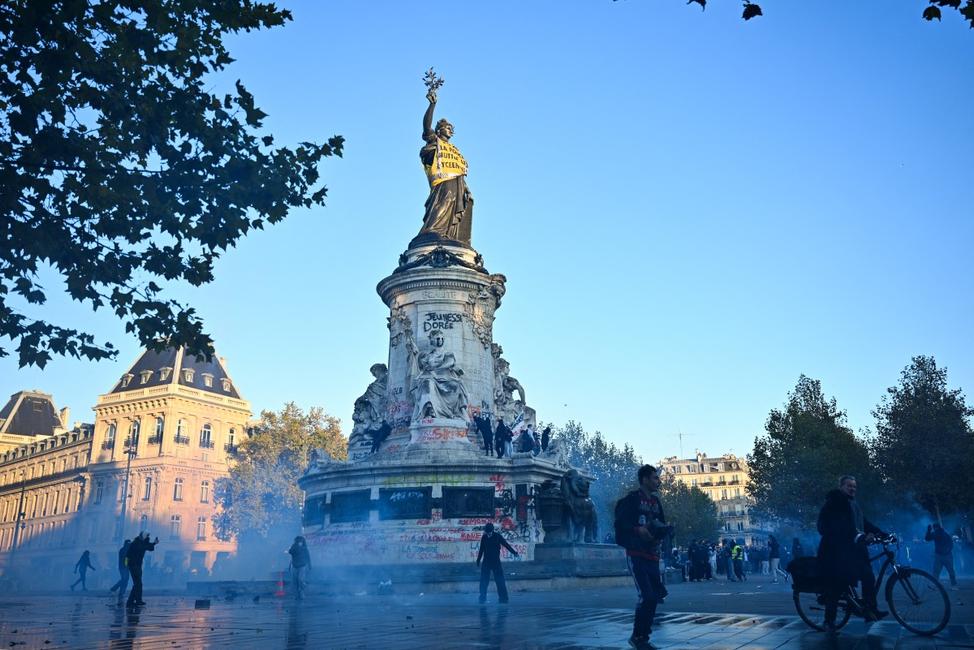 Des manifestants défilent près des gaz lacrymogènes et de la Statue de la République, rassemblés place de la République, après des affrontements survenus suite à une manifestation non autorisée dans le centre de Paris, le 18 octobre 2026, au lendemain des manifestations nationales contre le coût élevé de la vie.