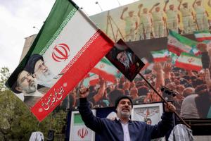 Un homme brandit un drapeau iranien affichant les visages des anciens et nouveaux dirigeants suprêmes iraniens, Ali et Mojtaba Khamenei, sur la place Enghelab (place de la Révolution) dans le centre de Téhéran, le 25 mars 2026.