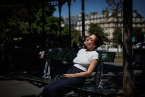 Une personne prend un bain de soleil sur un banc place de la Nation, à Paris, le 28 juillet 2026.