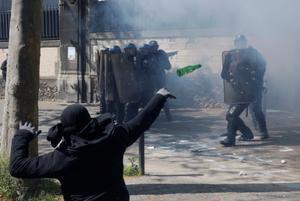 Un casseur lance une bouteille sur les forces de l'ordre à Paris en marge du défilé du 1er mai 2016