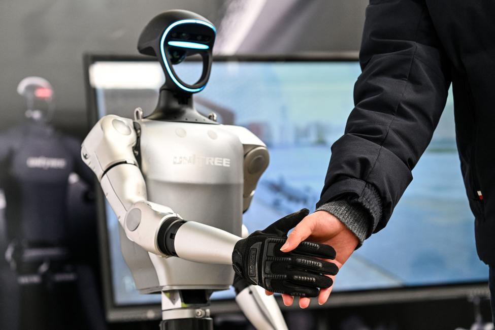 Un homme serre la main d'un robot humanoïde d'Unitree Robotics lors de la Global Developer Conference, organisée par la Shanghai AI Industry Association, à Shanghai, le 21 février 2025. (Image d'illustration)