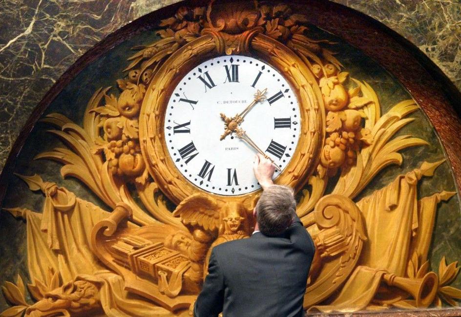 Une personne en train de changer l'heure d'une pendule.