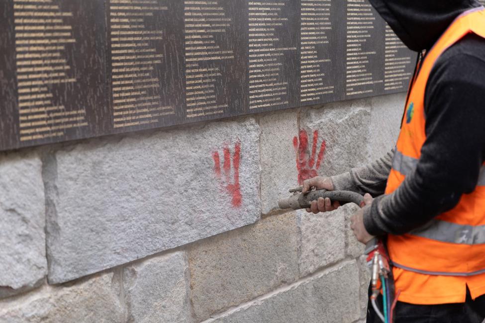 Un employé municipal nettoie le Mur des Justes, recouvert de graffitis de mains rouges, devant le Mémorial de la Shoah à Paris, le 14 mai 2024, après que le monument a été vandalisé dans la nuit. (Photo : Antonin UTZ / AFP)