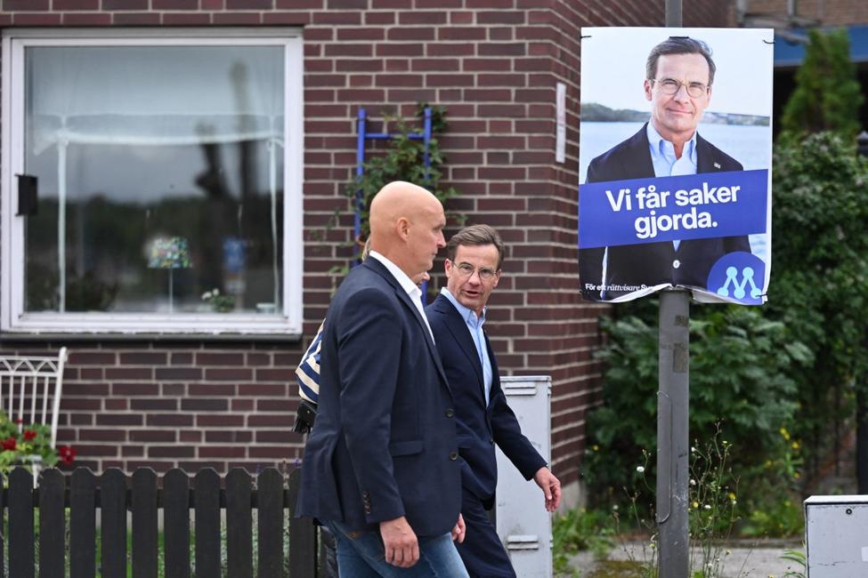 Le Premier ministre suédois Ulf Kristersson (à droite) passe devant une de ses affiches électorales en arrivant à un bureau de vote à Strangnas, près de Stockholm, pour voter lors des élections législatives suédoises du 13 septembre 2026.