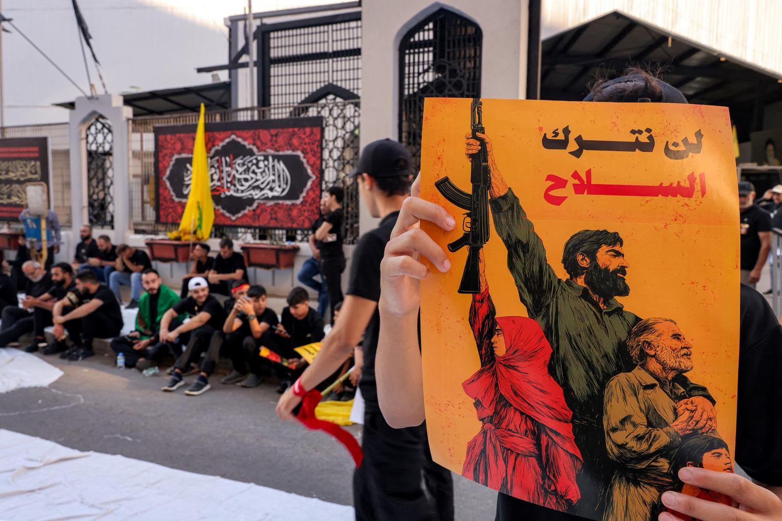 Une personne brandit une pancarte portant le slogan « Nous ne déposerons pas les armes » tandis que des partisans du Hezbollah chiite libanais participent à une cérémonie, dans la banlieue sud de Beyrouth, le 6 juillet 2025.