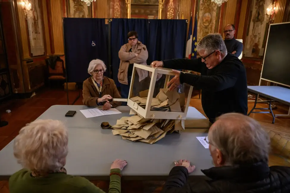 Des fonctionnaires vident une urne après la fermeture des bureaux de vote lors des élections municipales à la mairie de Perpignan, le 15 mars 2026.