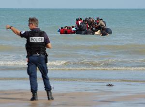 Des policiers tentent d'empêcher le départ d'un canot pneumatique transportant des migrants qui tentent de traverser illégalement la Manche pour rejoindre la Grande-Bretagne, sur la plage de Sangatte, dans le nord de la France, le 18 juillet 2023.