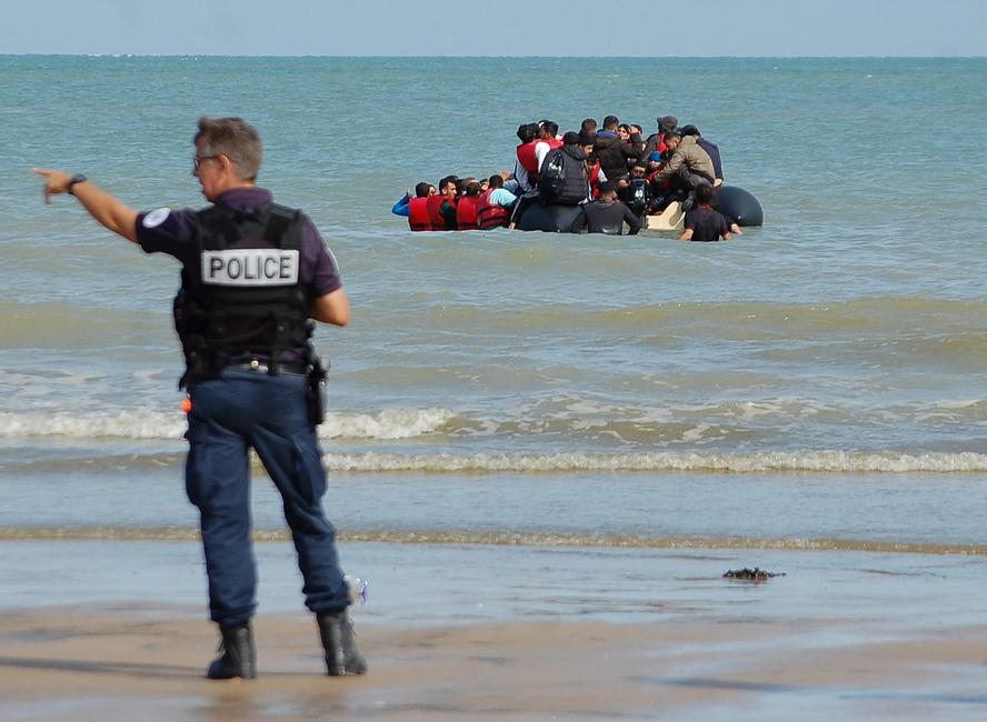 Des policiers tentent d'empêcher le départ d'un canot pneumatique transportant des migrants qui tentent de traverser illégalement la Manche pour rejoindre la Grande-Bretagne, sur la plage de Sangatte, dans le nord de la France, le 18 juillet 2023.