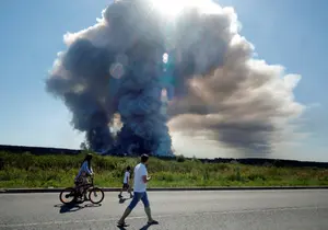 Des habitants passent devant la fumée d'un incendie survenu dans les complexes logistiques de l'entreprise russe de commerce en ligne Wildberries, à Elektrostal, près de Moscou, le 18 juillet 2026.