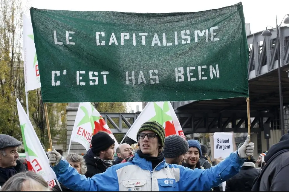 Un manifestant brandit une banderole contre le capitalisme.