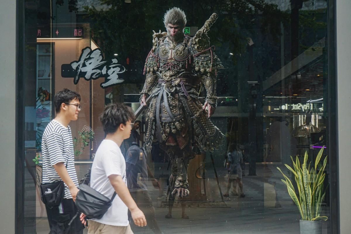 Des personnes passent devant l'image du personnage du « roi singe », ou « Sun Wukong », du jeu de rôle chinois « Black Myth : Wukong », développé par la société chinoise de jeux vidéo Game Science, lors de sa journée de lancement à Hangzhou, dans la province orientale du Zhejiang, le 20 août 2024.