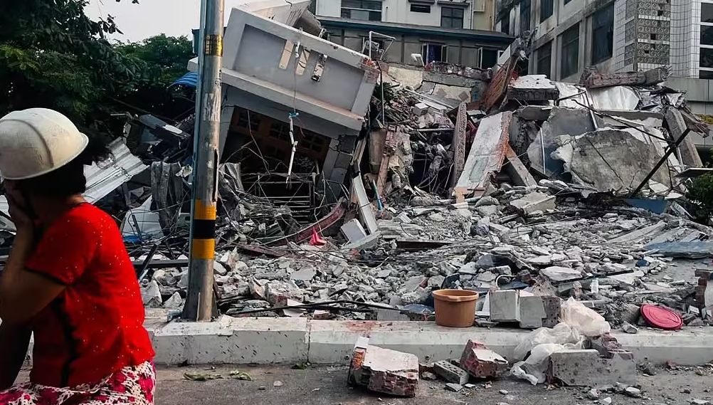 Un habitant observe un immeuble effondré à Mandalay, le 28 mars 2025, après un tremblement de terre dans le centre du Myanmar.