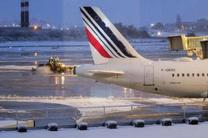 Une déneigeuse dégage le tarmac à côté d'un avion Air France à l'aéroport Roissy-Charles de Gaulle.