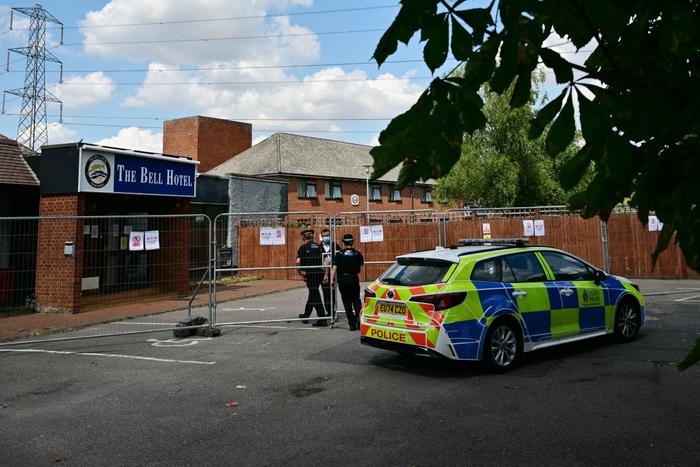 Des policiers pénètrent à travers une clôture à l'hôtel Bell, censé héberger des demandeurs d'asile, à Epping, au nord-est de Londres, le 18 juillet 2025, à la suite de manifestations anti-immigration.