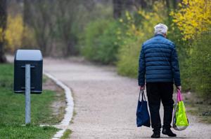Une personne âgée marche le long d'un chemin avec des sacs de courses, près d'Alexanderplatz à Berlin, le 27 mars 2025.