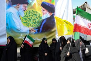 Une banderole avec une photo du guide suprême iranien, l'ayatollah Ali Khamenei, et du chef du Hezbollah libanais, Hassan Nasrallah, accrochée à un mur, tandis que des femmes iraniennes agitent des drapeaux nationaux lors d'une manifestation anti-israélienne à Téhéran, le 27 septembre 2024.
