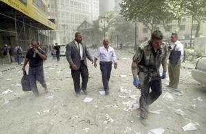 Un policier et d'autres personnes marchent dans les rues jonchées de débris près des tours du World Trade Center, le 11 septembre 2001 à New York. 