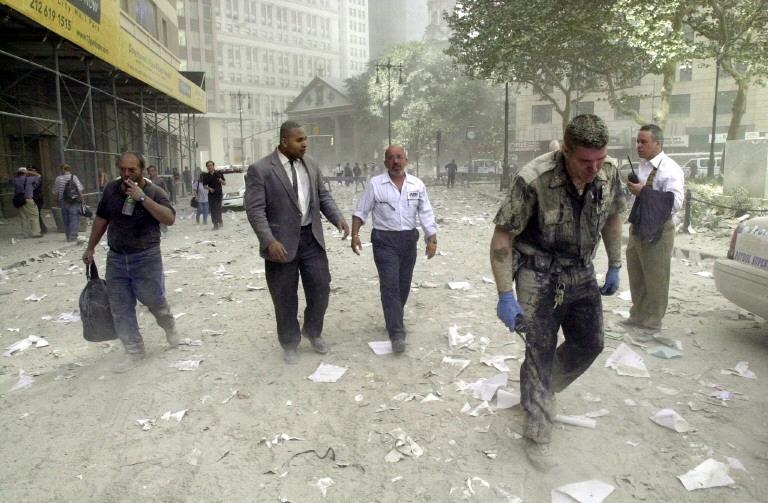 Un policier et d'autres personnes marchent dans les rues jonchées de débris près des tours du World Trade Center, le 11 septembre 2001 à New York. 