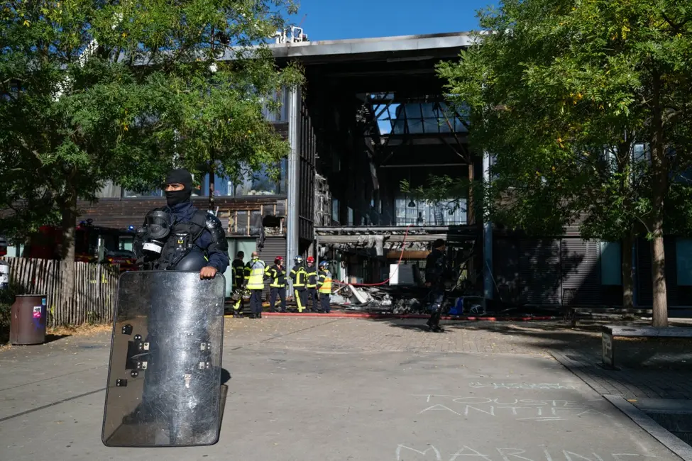 Un agent de sécurité observe les pompiers démanteler le hall d'entrée endommagé du lycée Nelson Mandela à Nantes, dans l'ouest de la France. Un incendie criminel a ravagé le hall de l'établissement, alors bloqué par des élèves.
