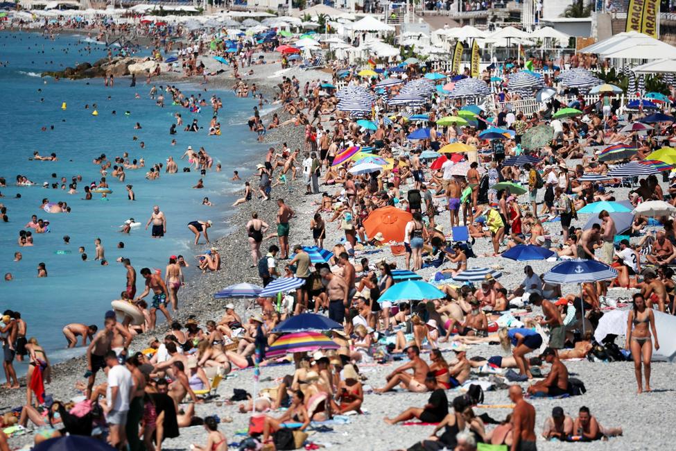 Des touristes profitent de la plage de la Promenade des Anglais à Nice, sur la Côte d'Azur, le 14 juillet 2025.