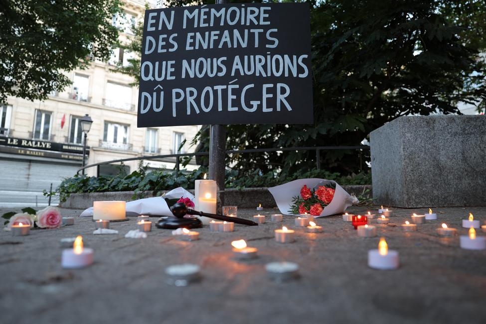 Cette photographie montre une pancarte sur laquelle est inscrit : « En mémoire des enfants que nous aurions dû protéger », lors d'une veillée aux chandelles organisée en hommage à Lyhanna, une collégienne française de 11 ans, le jour de ses obsèques, place des Droits de l'enfant à Paris, le 12 juin 2026.