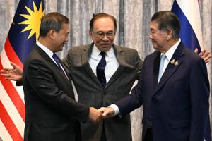 Le Premier ministre cambodgien Hun Manet (à gauche) et le Premier ministre par intérim thaïlandais Phumtham Wechayachai (à droite) se serrent la main tandis que le Premier ministre malaisien Anwar Ibrahim (au centre) les entoure de ses bras à l’issue d’une conférence de presse, après des discussions sur un possible cessez-le-feu entre la Thaïlande et le Cambodge à Putrajaya, le 28 juillet 2025.