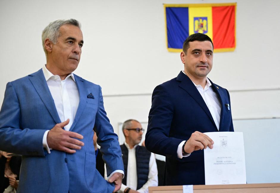 Le chef du parti nationaliste souverainiste « Alliance pour l'Union des Roumains » (AUR), George Simion, dépose son bulletin de vote aux côtés de l'ancien candidat Calin Georgescu lors du premier tour de l'élection présidentielle à Mogosoaia, le 4 mai 2025.