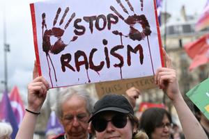 Un manifestant brandit une pancarte lors d'une manifestation place de la République à Paris, le 22 mars 2025, dans le cadre de la journée internationale contre le racisme et le fascisme.
