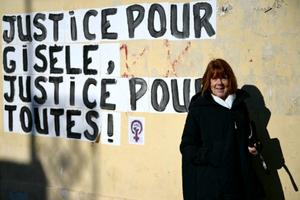 Gisèle Pelicot pose à côté d'un collage mural affichant le message « Justice pour Gisèle, justice pour toutes les femmes ! » lors du procès de son ancien compagnon, Dominique Pelicot, à Avignon, le 10 décembre 2024.