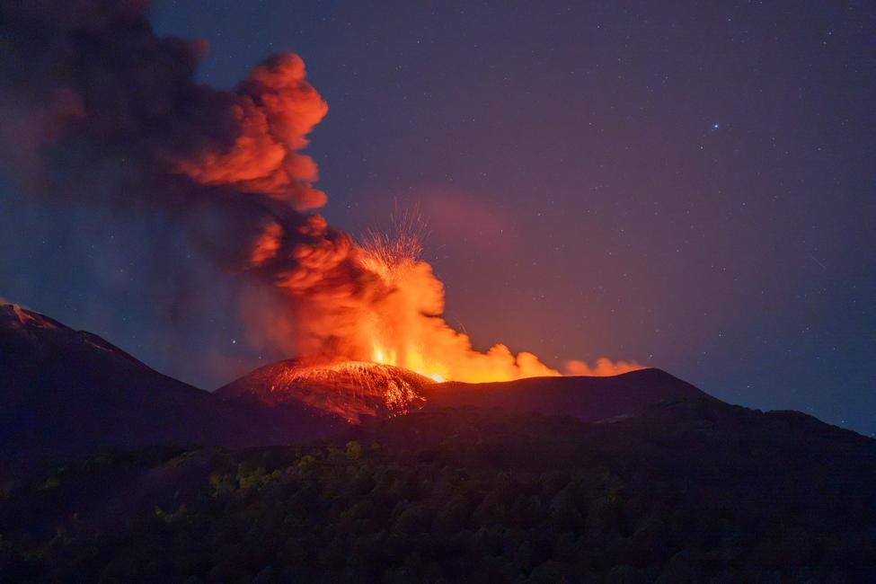 Une photographie prise le 5 juillet 2026 montre de la lave s'écoulant et de la fumée s'élevant du cratère lors d'une éruption du volcan Etna, en Sicile.