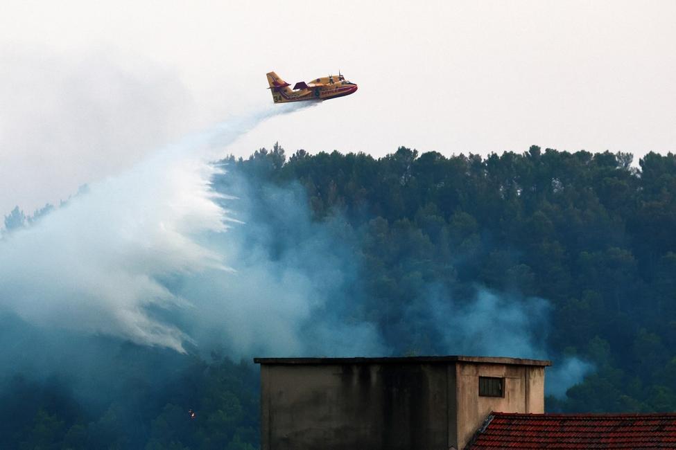 Un Canadair CL-415 de la Protection civile française largue de l'eau sur une zone en feu lors d'un incendie de forêt près de Barjols, dans le sud-est de la France, le 26 juillet 2026. 
