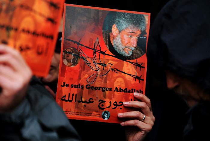 Un partisan du militant libanais Georges Ibrahim Abdallah brandit une pancarte portant son portrait et un slogan en français et en arabe.