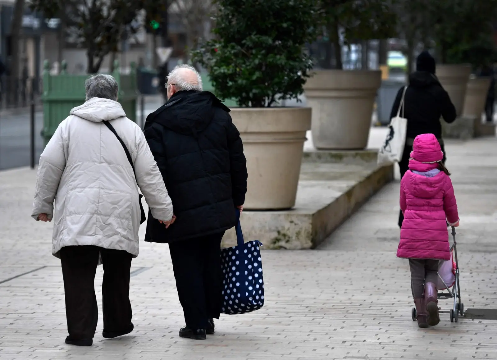 Un couple de personnes âgées marche main dans la main à côté d'une jeune fille à Vincennes,