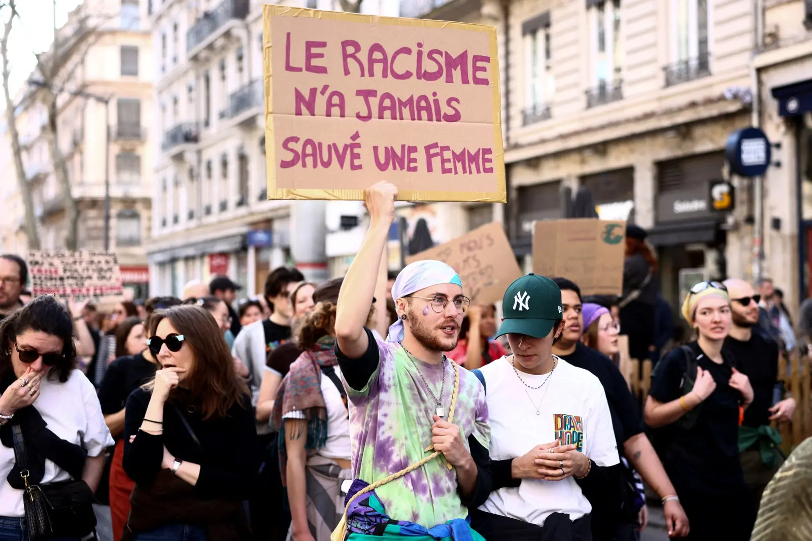 Un manifestant brandit une pancarte où l'on peut lire « Le racisme n'a jamais sauvé une femme » lors d'une marche organisée à Lyon, dans le centre de la France, le 8 mars 2026, à l'occasion de la Journée internationale des droits des femmes.