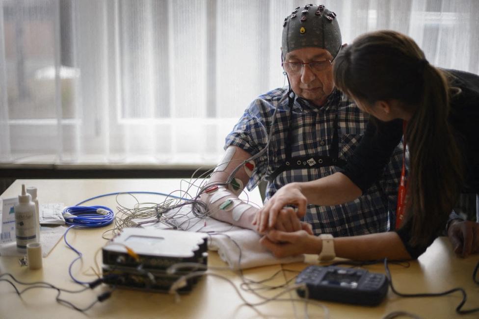 La physiothérapeute Vanessa Buhlmann tient la main d'un patient lors d'une présentation d'une interface cerveau-machine par l'École polytechnique fédérale de Lausanne (EPFL) à Sion.
