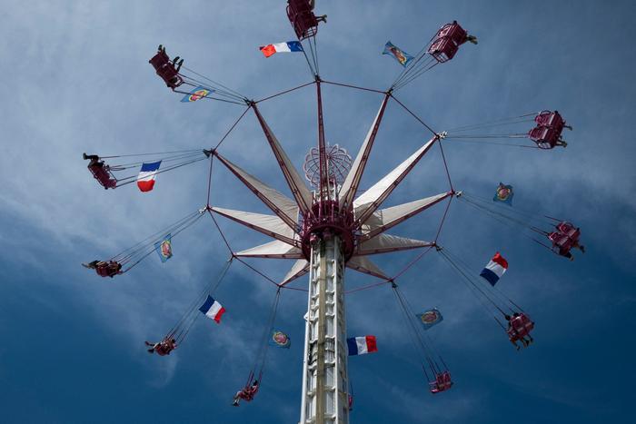 Des touristes profitent d’un manège dans une fête foraine ornée du drapeau français, à Paris. (Image d'illustration)