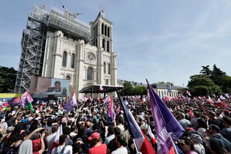 Des partisans brandissent des drapeaux du parti et des drapeaux français lors d'un rassemblement de lancement de la campagne présidentielle de Jean-Luc Mélenchon