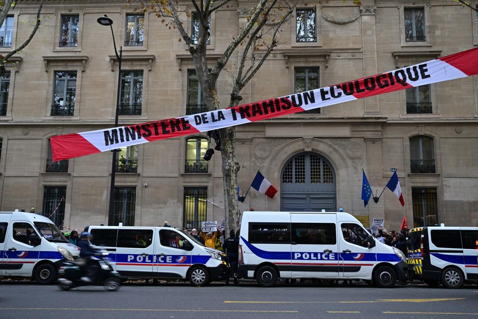 Une banderole portant l'inscription « Ministère de la trahison écologique » flotte devant des véhicules de police lors d'une action organisée par plusieurs organisations écologistes pour dénoncer les choix énergétiques du gouvernement, devant le ministère de la Transition écologique à Paris, le 6 novembre 2023.
