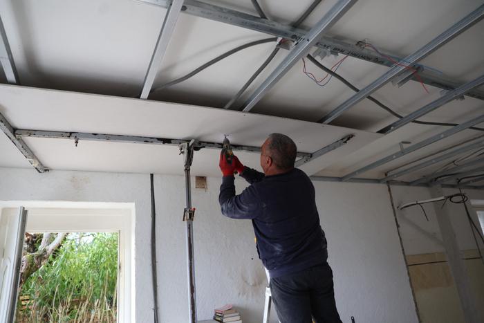 Un artisan installe un faux plafond en vue de la pose d'une isolation thermique dans une maison à Cognocoli-Monticchi, en Corse.
