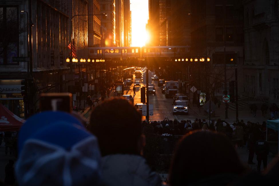 Photographes, touristes et habitants se rassemblent en centre-ville pour admirer le Chicagohenge le 22 mars 2025 à Chicago, dans l'Illinois. Lors du Chicagohenge, qui se produit au début du printemps et au début de l'automne, le soleil se lève et se couche exactement dans l'axe des rues est-ouest de Chicago, créant un moment idéal pour une photo entre les immeubles du centre-ville. Scott Olson/Getty Images/AFP (Photo de SCOTT OLSON / GETTY IMAGES NORTH AMERICA / Getty Images via AFP)