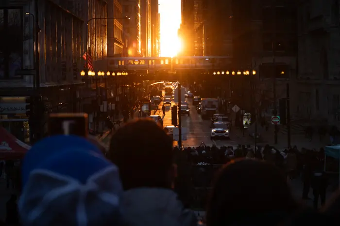 Photographes, touristes et habitants se rassemblent en centre-ville pour admirer le Chicagohenge le 22 mars 2025 à Chicago, dans l'Illinois. Lors du Chicagohenge, qui se produit au début du printemps et au début de l'automne, le soleil se lève et se couche exactement dans l'axe des rues est-ouest de Chicago, créant un moment idéal pour une photo entre les immeubles du centre-ville. Scott Olson/Getty Images/AFP (Photo de SCOTT OLSON / GETTY IMAGES NORTH AMERICA / Getty Images via AFP)