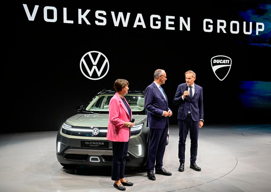 Hildegard Müller, présidente de l'Association allemande de l'industrie automobile (VDA), Friedrich Merz, chancelier allemand, et Oliver Blume, PDG du groupe Volkswagen (VW AG) sur le stand de Volkswagen lors de l'ouverture du Salon international de l'automobile de Munich (IAA), le 9 septembre 2025.