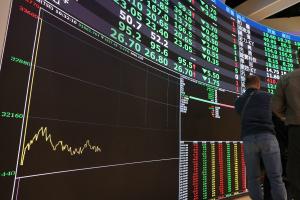 Des passants défilent devant un tableau affichant les cours des actions à la Bourse de Taïwan à Taipei, le 9 mars 2026.