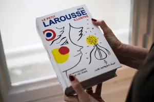 Une femme tient un exemplaire de la nouvelle édition du dictionnaire français « Petit Larousse ».