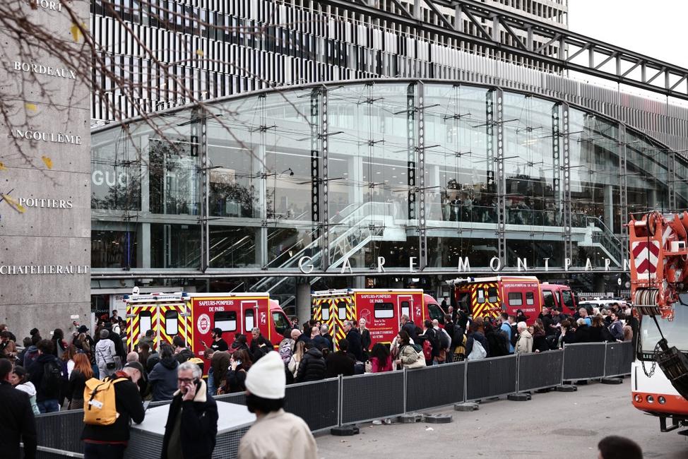 Des passagers attendent tandis que des fourgons de pompiers sont stationnés à l'entrée de la gare Montparnasse, à Paris, le 14 novembre 2025, après qu'un homme armé d'un couteau a été neutralisé par la police.