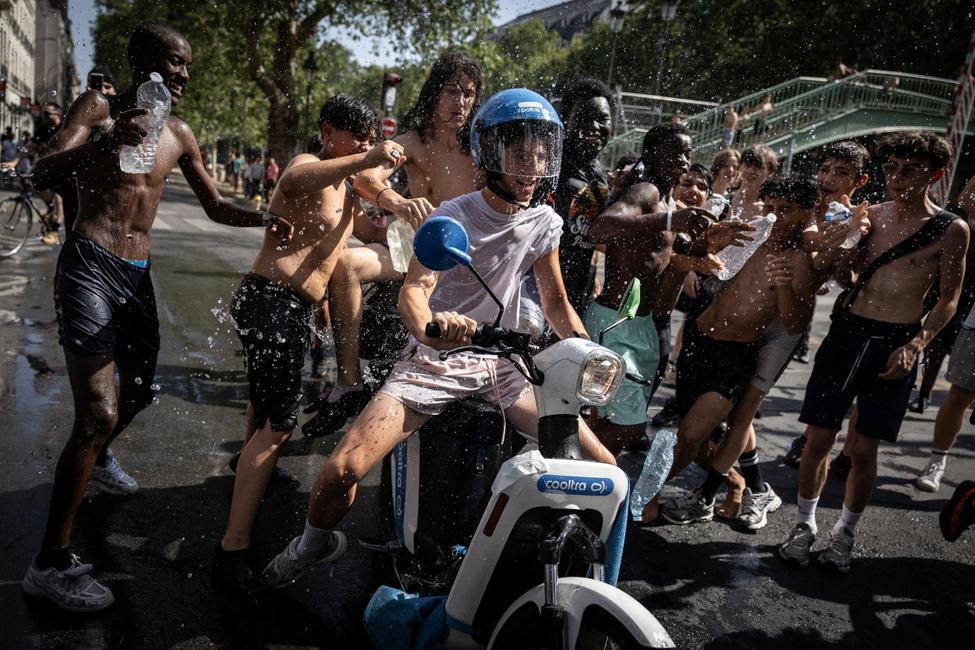Un groupe d'adolescents jette de l'eau sur un jeune homme conduisant un scooter près du canal Saint-Martin, à Paris, le 24 juin 2026, en pleine vague de chaleur.