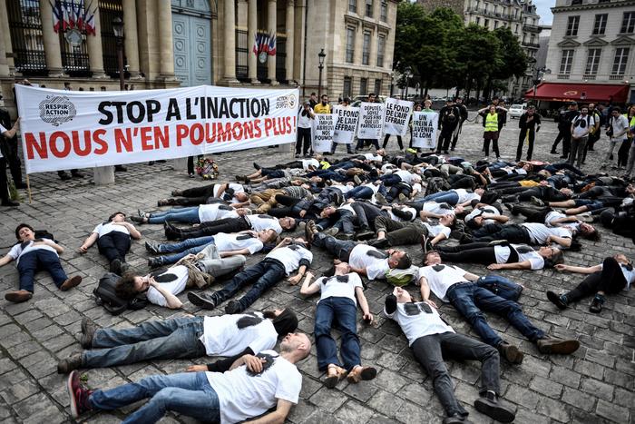 Des militants de l'association ANV-COP 21 pour le Climat organisent un « die-in » sous une banderole alors qu'ils participent à une manifestation pour dénoncer la qualité de l'air le 4 juin 2019 devant l'Assemblée nationale à Paris.(Image d'illustration)