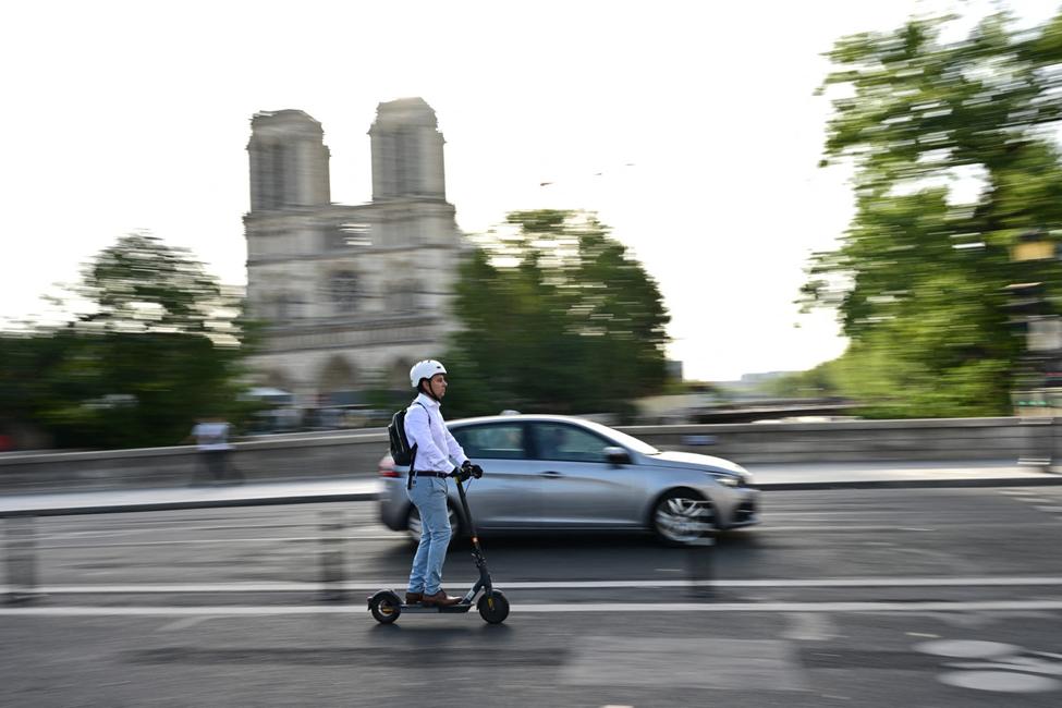 Un homme circule en trottinette électrique devant la cathédrale Notre-Dame de Paris.